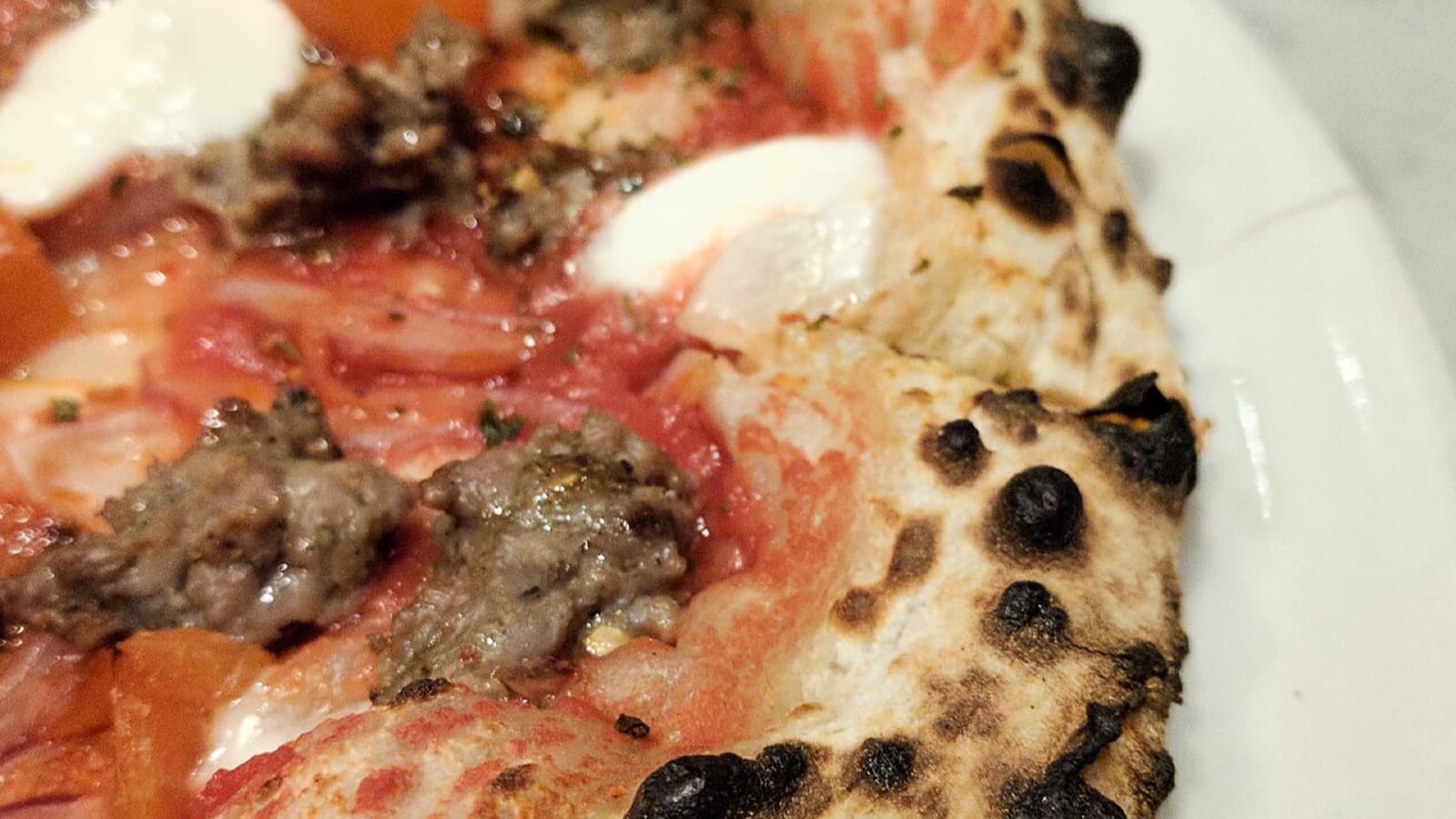 A blistered, naturally leavened Del Popolo wood-fired pizza, charred at the edges